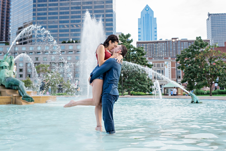 A man lifts his fiance up in the air for a kiss while standing in Swann Memorial Fountain in Center City Philadelphia.